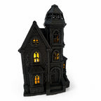 Blackthorn Manor illuminated haunted mansion with warm glowing windows in a front view
